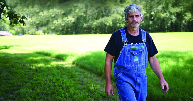 Craig Watts - chicken farmer - walking through a field