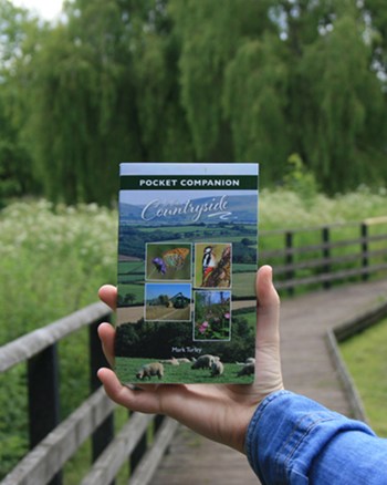hand holding countryside booklet in natural surroundings